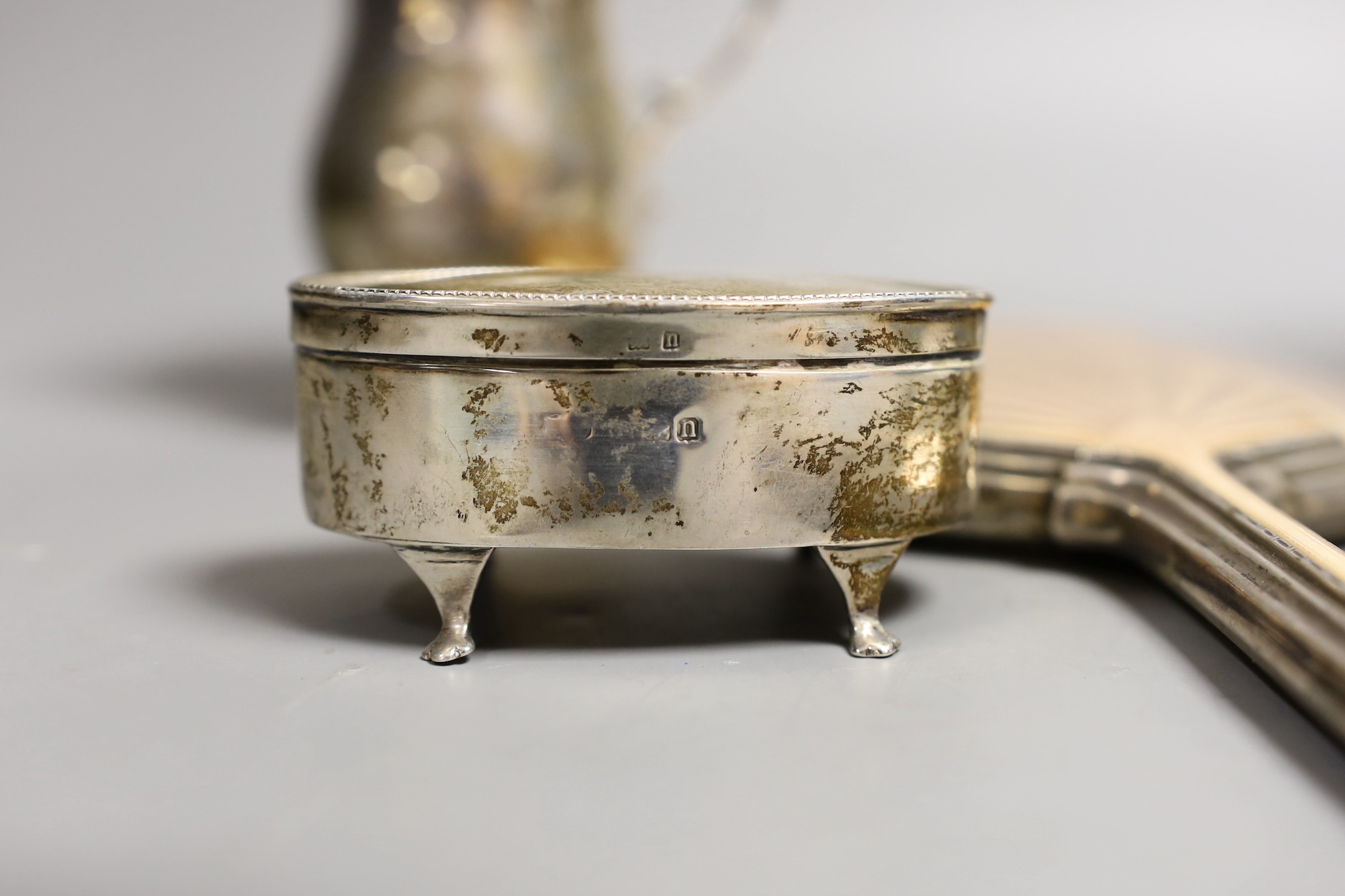 A George V silver two handled pedestal cup, Charles Edwards, London, 1923, height 13.2cm, an Art Deco silver and enamelled hand mirror, Birmingham, 1933, a silver oval trinket box, a silver cream jug and a pair of silver